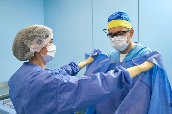 Enfermera Sala Preoperatoria Ayuda Cirujano Ponerse Una Bata Estéril Médicos —  Fotos de Stock
