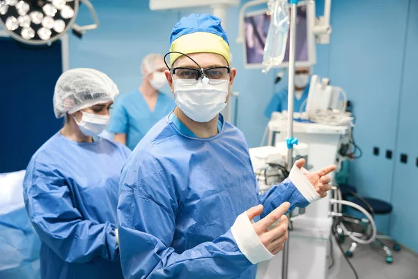 Хірург Одягнений Стерильну Сукню Перед Операцією Йому Допомагає Операційна Медсестра — стокове фото