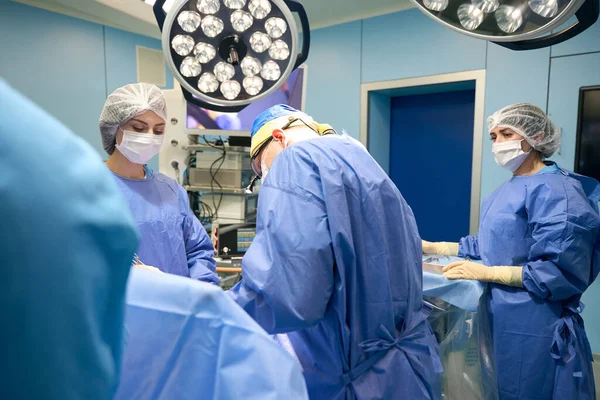 一组外科医生在现代化手术室 室内灯 监视器 外科设备中的工作 — 图库照片
