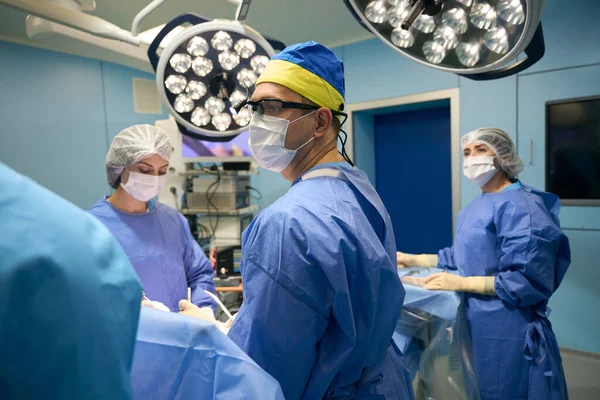 Cirurgião Com Uma Câmera Montada Cabeça Fica Mesa Operação Assistentes — Fotografia de Stock