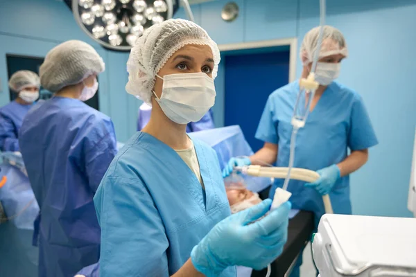 女性のアシスタントは 手術台で患者に薬の流れを制御します 背景外科医と麻酔科医で — ストック写真