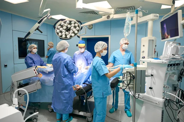 Surgical team works in a modern operating room, there is a lot of special equipment in the room