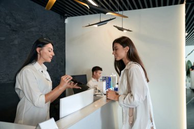 Masanın yanında duran gülümseyen yönetici ve hizmet listesini istemciye ver