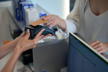 Müşteri hizmetleri masasının yanında duran ve hizmetleri kredi kartıyla ödeyen kadın.