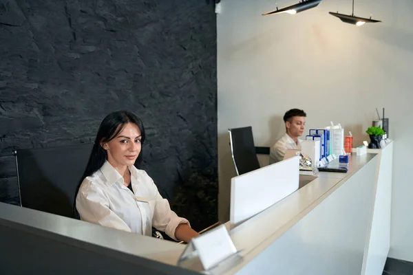 Mujer Joven Trabajando Ordenador Junto Asistente Mirando Cámara Esperando Clientes — Foto de Stock