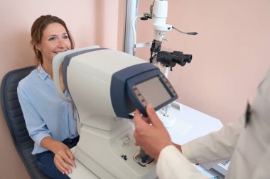 Doktor klinikte koordine makinesini çalıştırırken neşeli kadının portresi yarık lambanın önünde oturuyor.