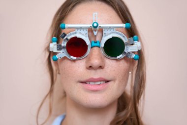 Zarif beyaz kadının portresi göz hekimliği kliniğindeki diyopter seçimine bakıyor.