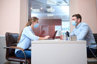 Yakışıklı beyaz bir erkek ve güzel bir kadının belden yukarısı portresi modern parlak ofiste tartışılıyor.