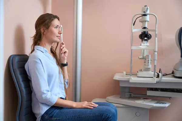 在眼科诊所检查她的视力时 美丽的高加索女性正坐在椅子上 腰部朝上看画像 — 图库照片