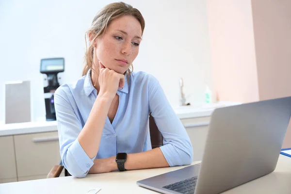 一位优雅的高加索女人坐在室内的办公桌前 她的近照正看着笔记本电脑的屏幕 — 图库照片