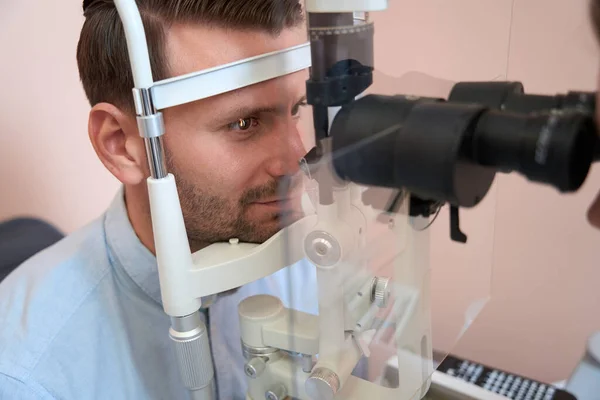 stock image Close up side view portrait of handsome confident male is getting professional checking visual acuity in optician center