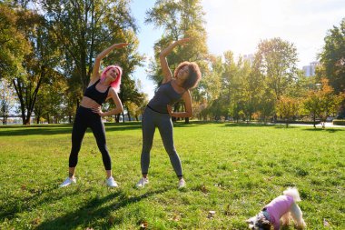 Kamu parkında yan köşe yapan iki melez kadının tam boy portresi