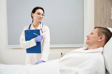 Üniformalı zarif beyaz kadın doktorun ön manzara portresi, hastanedeki hasta odasındaki teşhis semptomudur.