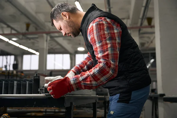 Ενήλικες Άνδρας Προστατευτικά Γάντια Που Εξετάζουν Προσεκτικά Δομή Του Σιδήρου — Φωτογραφία Αρχείου