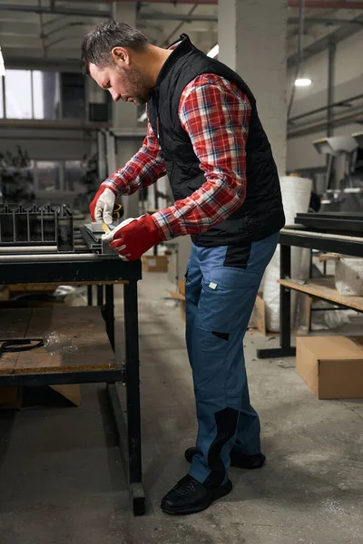 Άνδρας Προστατευτικά Γάντια Που Εξετάζει Προσεκτικά Μεταλλική Δομή Και Λαμβάνει — Φωτογραφία Αρχείου