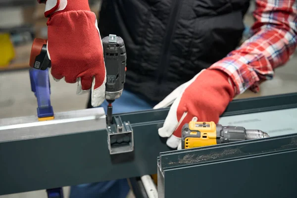 男工在车间用电动螺丝刀连接两个钢制细部 — 图库照片