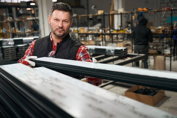 Mężczyzna Układania Profilu Stosie Fabryce Konstrukcji Metalowych Patrząc Aparat — Zdjęcie stockowe