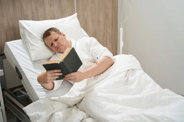 美丽的白种人男子的蜡像躺在病床上 在医院看书 — 图库照片