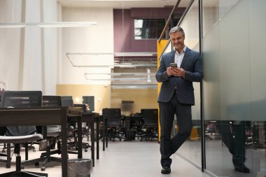 Adult male in office clothes standing in coworking, looking at camera and chatting clipart