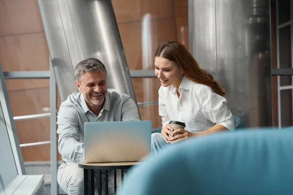 快乐的女士和男人坐在笔记本电脑旁的办公室里 看着屏幕 一起工作 — 图库照片