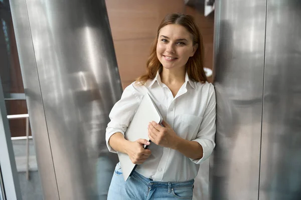 Ofiste Elinde Dizüstü Bilgisayarla Kameraya Bakan Mutlu Genç Bir Kadın — Stok fotoğraf