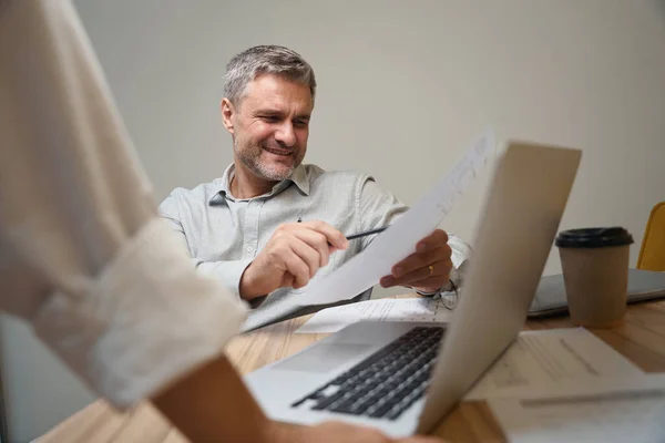 Hombre Adulto Sentado Junto Mesa Cerca Computadora Portátil Coworking Sosteniendo —  Fotos de Stock