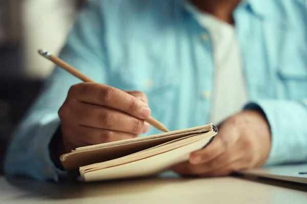 男人坐在桌旁的椅子上 用铅笔在商务中心写日记 — 图库照片