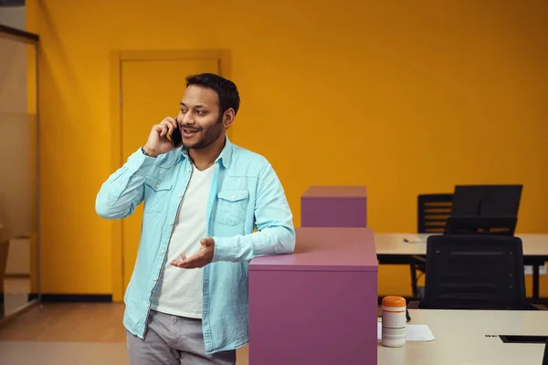 笑顔の男性がテーブルの近くに立って ビジネスセンターの仕事で電話をかける — ストック写真