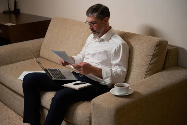 Vuxen Man Affärskläder Sitter Soffan Håller Laptop Och Läser Dokument — Stockfoto