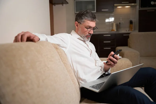 Adamı Kanepede Oturuyor Dizüstü Bilgisayarını Tutuyor Müşteriyle Telefonda Konuşuyor Çalışıyor — Stok fotoğraf