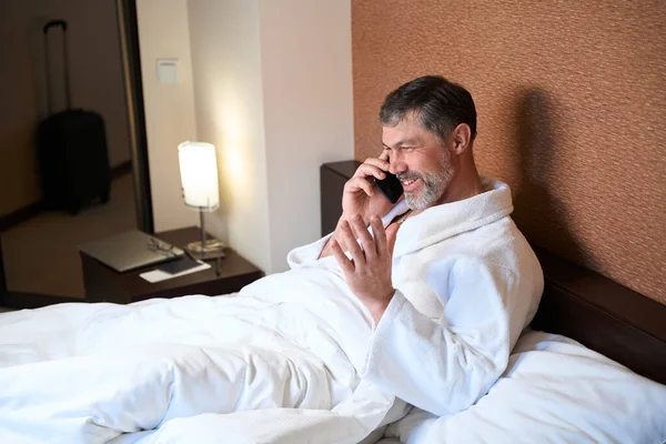 Adult Male Bathrobe Sitting Bed Holding Mobile Phone Talking Hotel — Stock Photo, Image