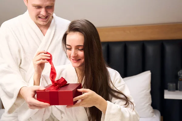 迷人的女人带着礼物打开一个盒子 这是她的男朋友 祝她情人节快乐 — 图库照片
