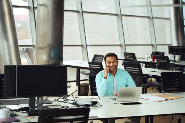 幸せな男性は コンピュータで椅子に座って オフィスで働くためにスマートフォンを使用して — ストック写真
