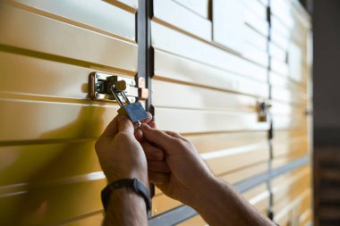 Kasadaki dolabın kilidini kullanarak erkek eli kesilen fotoğraf.