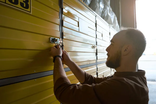 収納室の荷物ロッカーから鍵を開ける男の集中的な側面図 — ストック写真