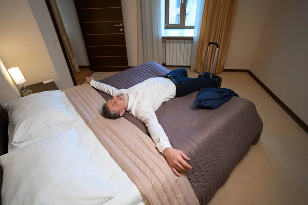 Dorosły Mężczyzna Ubraniu Biurowym Spoczywający Łóżku Pobliżu Walizki Hotelu — Zdjęcie stockowe