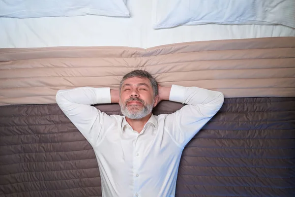 在酒店里 穿着办公室服装的成年人躺在床上放松的近照 — 图库照片