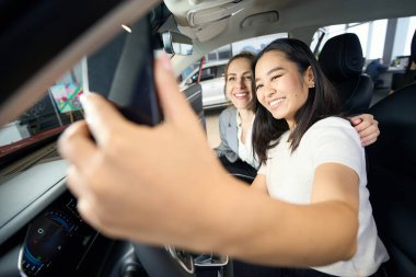 Arabada ön koltukta selfie çeken iki mutlu kadın.