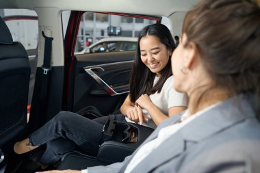 Gülümseyen çarpıcı kadın otomobilde oturup panele bakıyor.