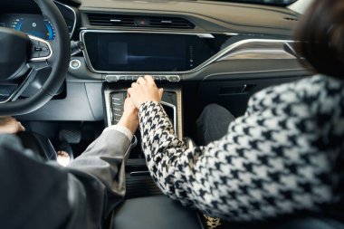 Ceketli iki kadının elleri vites kutusunda birbirlerinin üzerinde dinleniyor.