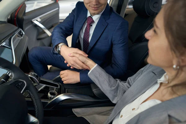 坐在汽车前座上的商人和女士正在握手 — 图库照片