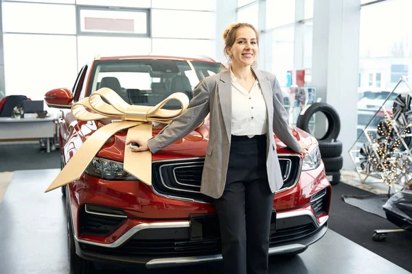 Leende Kvinna Kostym Står Framför Röd Bil Autodealership — Stockfoto
