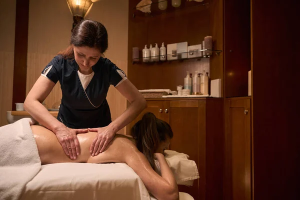 Massaggiatrice Concentrata Vestita Uniforme Impastare Muscoli Posteriori Del Cliente Femminile — Foto Stock