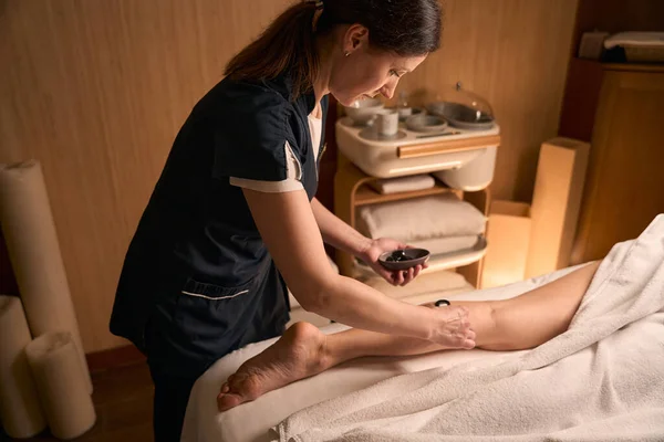 Serious Cosmetologist Applying Brown Algae Paste Woman Lower Leg Spatula — Stock Photo, Image
