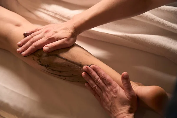 Foto Ritagliata Massaggiatrice Mani Sfregamento Gamba Donna Con Pasta Alghe — Foto Stock