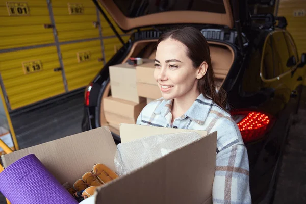 满脸笑容的成年女人在仓库的汽车旁边放着装有货物的盒子 — 图库照片