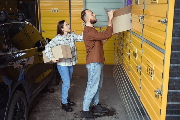两个忙碌的人站在汽车旁边 把一盒东西堆在储物柜里 — 图库照片