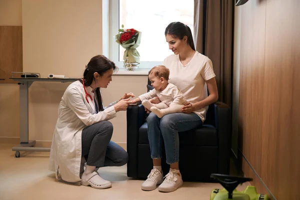 Allvarlig Pediatrisk Läkare Kontrollerar Greppreflex Hos Liten Patient Sittande Moderknät — Stockfoto