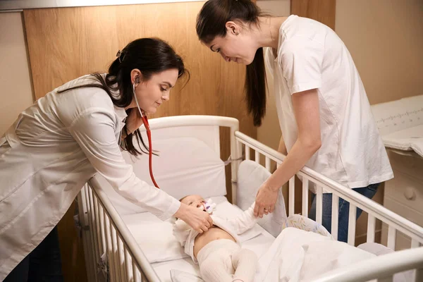 의사가 어머니가 기뻐하는 가운데 청진기로 아기의 소리를 — 스톡 사진