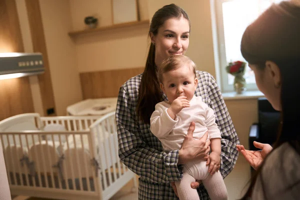 Zufriedene Frau Mit Säugling Arm Steht Während Des Gesprächs Vor — Stockfoto